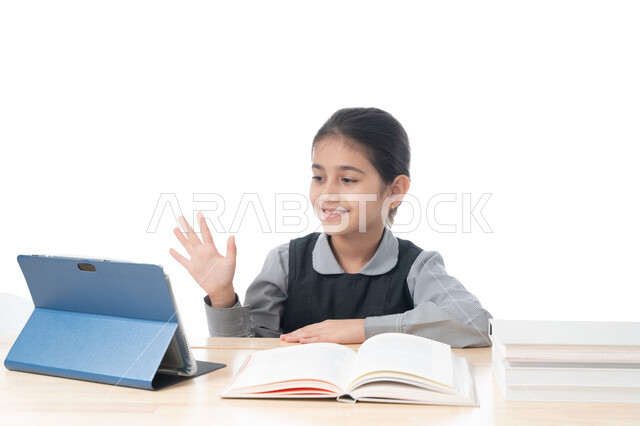 ايماءات السعادة والفرح لمعرفة الجواب، المشاركة الفعالة للطلاب، بورتريه لتلميذة عربية خليجية اماراتية ترتدي الزي المدرسي تحضر دروسها عن طريق جهاز التابلت الإلكتروني، طالبة سعودية تجلس على طاولة الدارسة ترفع يدها للإجابة، خلفية بيضاء