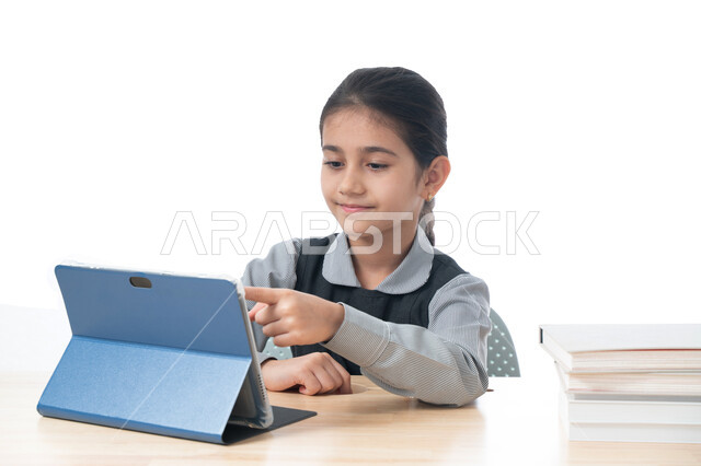 اكاديميات ومدارس حديثة، طرق تعلمية جديدة ومتطورة، بورتريه لطالبة عربية خليجية اماراتية ترتدي اليونيفورم المدرسي تقوم بمتابعة الدروس باستخدام جهاز التابلت الحديث، تلميذة سعودية تشير إلى سؤال ما، مفهوم التعليم الإلكتروني، خلفية بيضاء