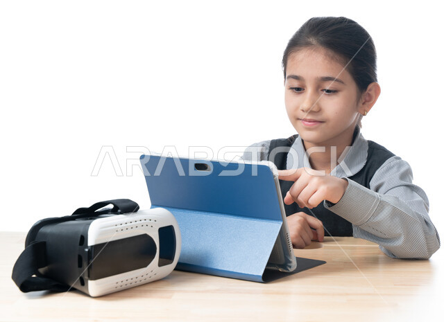 طرائق تعلمية جديدة متطورة، بورتريه لطالبة عربية خليجية اماراتية ترتدي الزي المدرسي تقوم بمتابعة الدروس باستخدام جهاز التابلت الحديث، تلميذة سعودية تشير إلى سؤال ما، اكاديميات ومدارس حديثة، مفهوم التعليم الإلكتروني، نظارات الواقع الافتراضي، خلفية بيضاء