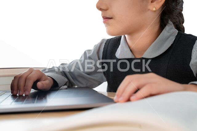 المذاكرة و الدراسة عن بعد، بورترية مقرب لتلميذة خليجية عربية إماراتية ترتدي مريول المدرسة و تدرس في المنزل، مفهوم التعليم الإلكتروني، طالبة سعودية مجتهدة تراجع دروسها من الكتب وتستخدم الحاسوب المحمول، متابعة الحصص و حل الواجبات عبر الانترنت، خلفية بيضاء