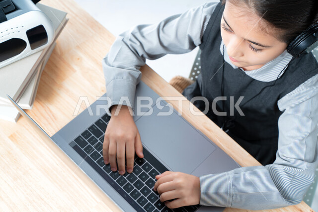  التحضير للإمتحانات و الإختبارات النهائية، طالبة سعودية تذاكر دروسها من الحاسوب، بورترية مقرب لتلميذة خليجية عربية إماراتية ترتدي الزي المدرسي و سماعة الرأٍس، حضور البث المباشر للحصص الاونلاين عن طريق الكمبيوتر، مفهوم التعليم الإلكتروني، خلفية بيضاء