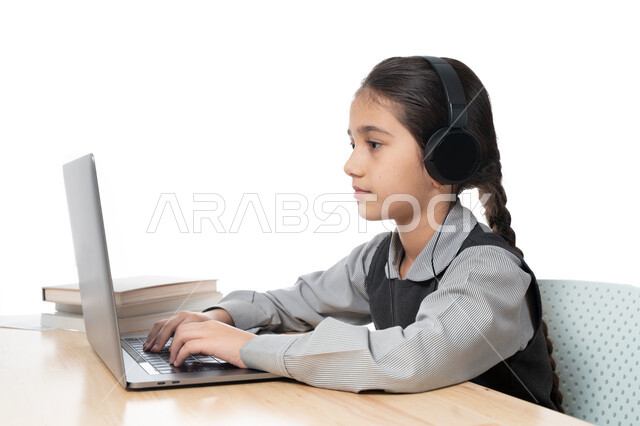 حضور البث المباشر للحصص الاونلاين عن طريق الكمبيوتر، بورترية مقرب لتلميذة خليجية عربية إماراتية ترتدي الزي المدرسي و سماعة الرأٍس،  مفهوم التعليم الإلكتروني، طالبة سعودية تذاكر دروسها من الحاسوب، الإستعداد للإمتحانات و الإختبارات النهائية ، خلفية بيضاء