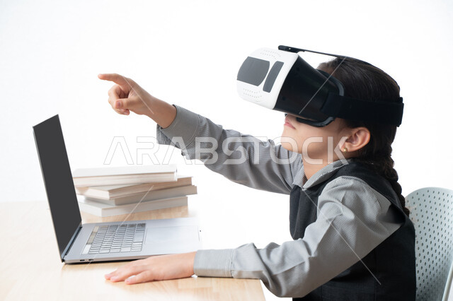 حل الواجبات عبر الانترنت، بورترية مقرب لتلميذة خليجية عربية إماراتية ترتدي اليونيفورم و تشير الى شيئ ما، متابعة حصص الاونلاين عن طريق الكمبيوتر، مفهوم التعليم الإلكتروني، طفلة سعودية ترتدي نظارات الواقع الإفتراضي وتتفاعل مع البث المباشر، خلفية بيضاء