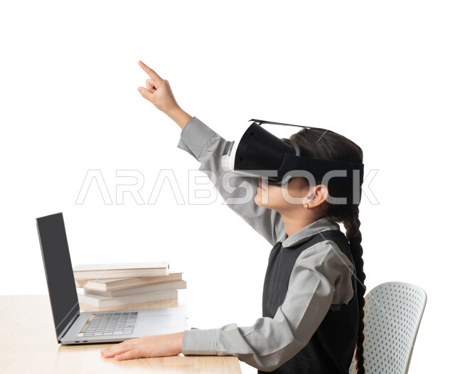 حل الواجبات عبر الانترنت، بورترية مقرب لتلميذة خليجية عربية إماراتية ترتدي اليونيفورم و تشير الى شيئ ما، متابعة حصص الاونلاين عن طريق الكمبيوتر، مفهوم التعليم الإلكتروني، طفلة سعودية ترتدي نظارات الواقع الإفتراضي وتتفاعل مع البث المباشر، خلفية بيضاء