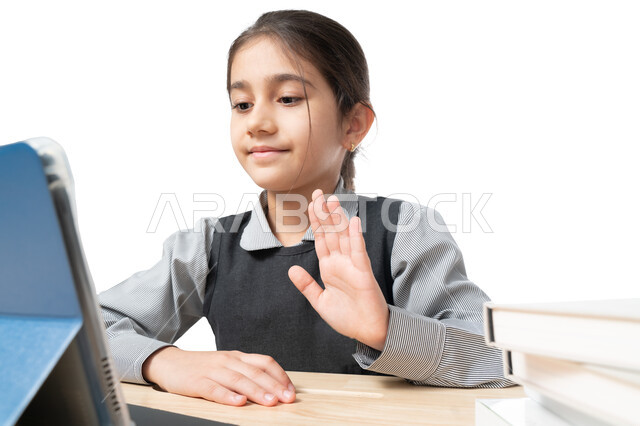 المشاركة الفعالة للطلاب ومتابعة الواجبات من خلال منصة التعلم عن بعد, بورتريه مقرب لتلميذة عربية خليجية إماراتية ترتدي المريول المدرسي وتتابع درس الأونلاين عبر التابليت, طالبة سعودية تحضر الحصص الدراسية عبر الانترنت, التعليم الالكتروني المنزلي، خلفية بيضاء