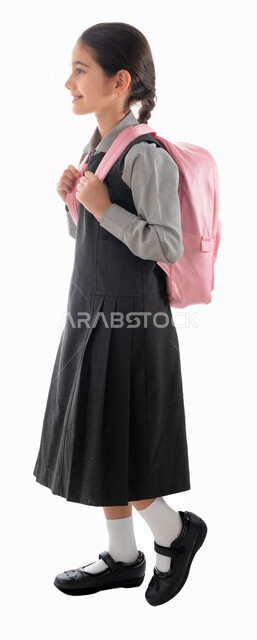 موسم العوده للمدارس, التهيئة والتجهيز لبداية العام الدراسي, بورتريه من الجانب لطالبة عربية خليجية اماراتية ترتدي الزي المدرسي وتحمل الحقيبة المدرسية, تلميذه سعودية مجتهده ومتميزه, ايماءات المشي إلى المدرسه, صورة الجسم بالطول الكامل, خلفية بيضاء.