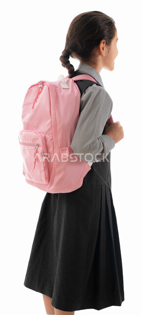 Paying attention to the arrangement and external appearance, stationery and modern school bags for girls, a portrait from behind of an Arab Gulf Emirati student wearing a school apron and carrying a backpack, an elegant and tidy Saudi student, the beginni