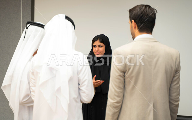 أستاذه جامعيه عربيه إماراتية خليجيه تشرح لطلابها المحاضره, مدربه جامعيه,طلاب إماراتيون يقفنا أمام الأستاذة ويتم  تدوين الملاحظات على جهاز الحاسب , التعليم الجامعي في الإمارات العربية المتحدة , فريق عمل عربي إماراتي  خليجي