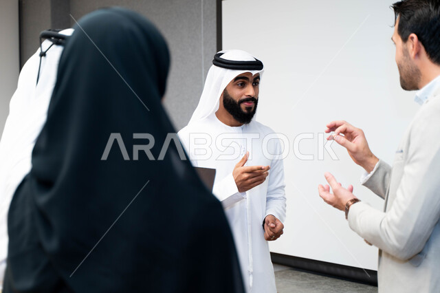 أستاذ جامعي عربي إماراتي خليجي يشرح لطلابه المحاضره, طلاب إماراتيون يقفنا أمام الاستاذ و يتم تدوين الملاحظات على جهاز الحاسب , فريق عمل عربي إماراتي  خليجي, الإجتماع في مقر العمل, مناقشة مهام العمل, تحقيق الأهداف, تدريب الموظفين, ورشة عمل