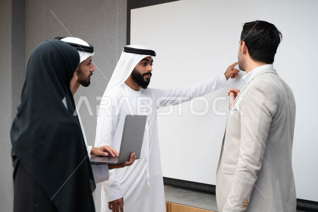 أستاذ جامعي عربي إماراتي خليجي يشرح لطلابه المحاضره, طلاب إماراتيون يقفنا أمام الاستاذ و يتم تدوين الملاحظات على جهاز الحاسب , فريق عمل عربي إماراتي  خليجي, الإجتماع في مقر العمل, مناقشة مهام العمل, تحقيق الأهداف, تدريب الموظفين, ورشة عمل