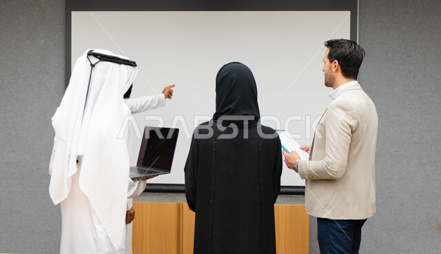 أستاذ جامعي عربي إماراتي خليجي يشرح لطلابه المحاضره, طلاب إماراتيون يقفنا أمام الاستاذ و يتم تدوين الملاحظات على جهاز الحاسب , فريق عمل عربي إماراتي  خليجي, الإجتماع في مقر العمل, مناقشة مهام العمل, تحقيق الأهداف, تدريب الموظفين, ورشة عمل