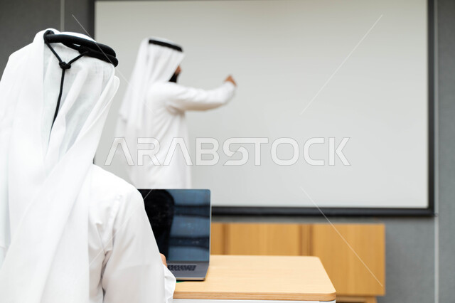 أستاذ جامعي عربي إماراتي خليجي يشرح لطلابه المحاضره, مدرب جامعي, تدوين الملاحظات على السبوره, التعليم الجامعي في الإمارات العربية المتحدة , فريق عمل عربي إماراتي خليجي, الإجتماع في مقر العمل, مناقشة مهام العمل, تحقيق الأهداف, تدريب الموظفين, ورشة عمل