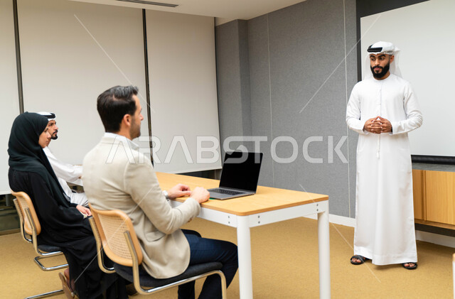An Arab-Emirati-Gulf university professor explaining to his students the lecture, a university trainer, taking notes on the board, university education in the United Arab Emirates, an Arab-Emirati-Gulf team, meeting at the workplace, discussing work tasks
