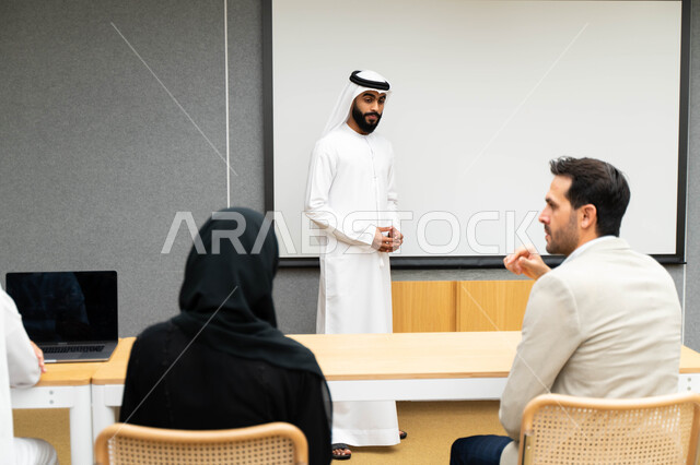 أستاذ جامعي عربي إماراتي خليجي يشرح لطلابه المحاضره, مدرب جامعي, تدوين الملاحظات على السبوره, التعليم الجامعي في الإمارات العربية المتحدة , فريق عمل عربي إماراتي خليجي, الإجتماع في مقر العمل, مناقشة مهام العمل, تحقيق الأهداف, تدريب الموظفين, ورشة عمل