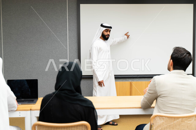 أستاذ جامعي عربي إماراتي خليجي يشرح لطلابه المحاضره, مدرب جامعي, تدوين الملاحظات على السبوره, التعليم الجامعي في الإمارات العربية المتحدة , فريق عمل عربي إماراتي خليجي, الإجتماع في مقر العمل, مناقشة مهام العمل, تحقيق الأهداف, تدريب الموظفين, ورشة عمل