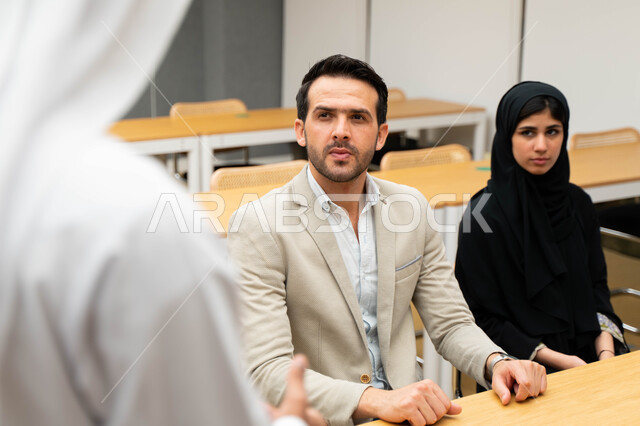 أستاذ جامعي عربي إماراتي خليجي يشرح لطلابه المحاضره, مدرب جامعي, تدوين الملاحظات على السبوره, التعليم الجامعي في الإمارات العربية المتحدة , فريق عمل عربي إماراتي خليجي, الإجتماع في مقر العمل, مناقشة مهام العمل, تحقيق الأهداف, تدريب الموظفين, ورشة عمل