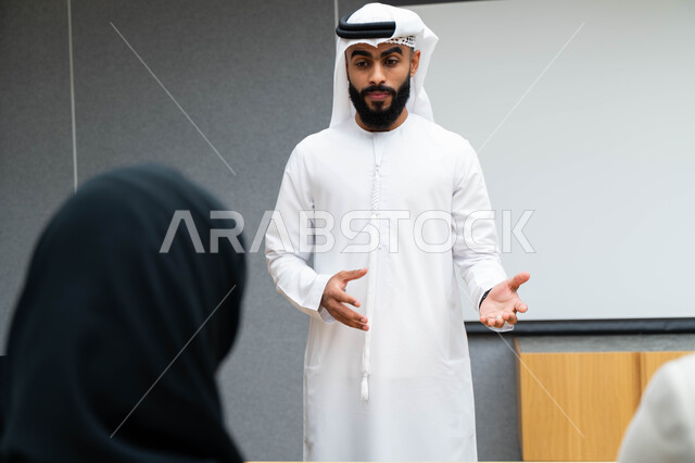 أستاذ جامعي عربي إماراتي خليجي يشرح لطلابه المحاضره, مدرب جامعي, تدوين الملاحظات على السبوره, التعليم الجامعي في الإمارات العربية المتحدة , فريق عمل عربي إماراتي خليجي, الإجتماع في مقر العمل, مناقشة مهام العمل, تحقيق الأهداف, تدريب الموظفين, ورشة عمل