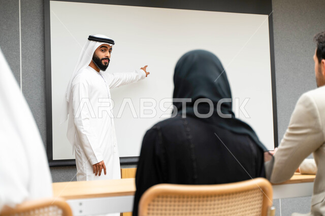 أستاذ جامعي عربي إماراتي خليجي يشرح لطلابه المحاضره, مدرب جامعي, تدوين الملاحظات على السبوره, التعليم الجامعي في الإمارات العربية المتحدة , فريق عمل عربي إماراتي خليجي, الإجتماع في مقر العمل, مناقشة مهام العمل, تحقيق الأهداف, تدريب الموظفين, ورشة عمل