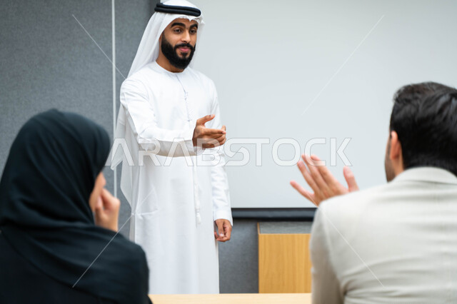 أستاذ جامعي عربي إماراتي خليجي يشرح لطلابه المحاضره, مدرب جامعي, تدوين الملاحظات على السبوره, التعليم الجامعي في الإمارات العربية المتحدة , فريق عمل عربي إماراتي خليجي, الإجتماع في مقر العمل, مناقشة مهام العمل, تحقيق الأهداف, تدريب الموظفين, ورشة عمل