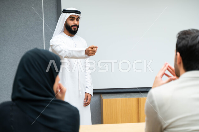 أستاذ جامعي عربي إماراتي خليجي يشرح لطلابه المحاضره, مدرب جامعي, تدوين الملاحظات على السبوره, التعليم الجامعي في الإمارات العربية المتحدة , فريق عمل عربي إماراتي خليجي, الإجتماع في مقر العمل, مناقشة مهام العمل, تحقيق الأهداف, تدريب الموظفين, ورشة عمل