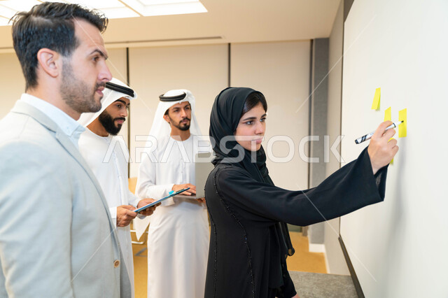 استاذة جامعيه عربيه إماراتيه خليجيه تشرح لطلابها المحاضره, مدربه جامعيه, تدوين الملاحظات على السبوره, التعليم الجامعي في الإمارات المتحدة , فريق عمل عربي إماراتي خليجي, الإجتماع في مقر العمل, مناقشة مهام العمل, تحقيق الأهداف, تدريب الموظفين, ورشة عمل