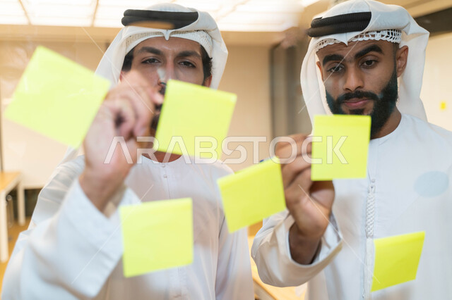 مجموعة طلاب عرب إماراتيون  خليجيون في مقر الجامعة , تدوين الملاحظات والمهام على الورق، مناقشة و تحديد الاهداف، أساتذه في الجامعه, مناقشة مشروع, التعليم الجامعي, مدربين جامعيين, وحدة العمل الجماعي, ورشة عمل