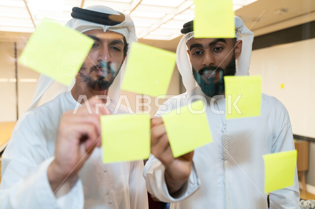 مجموعة طلاب عرب إماراتيون  خليجيون في مقر الجامعة , تدوين الملاحظات والمهام على الورق، مناقشة و تحديد الاهداف، أساتذه في الجامعه, مناقشة مشروع, التعليم الجامعي, مدربين جامعيين, وحدة العمل الجماعي, ورشة عمل