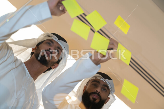 مجموعة طلاب عرب إماراتيون  خليجيون في مقر الجامعة , تدوين الملاحظات والمهام على الورق، مناقشة و تحديد الاهداف، أساتذه في الجامعه, مناقشة مشروع, التعليم الجامعي, مدربين جامعيين, وحدة العمل الجماعي, ورشة عمل