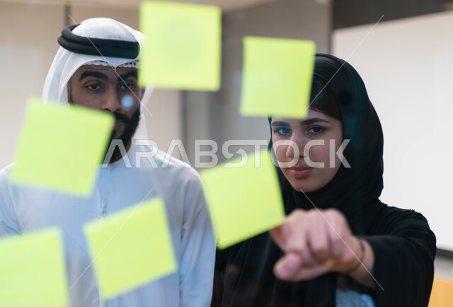 فريق طلاب و طالبات  عرب إماراتيون  خليجيون في مقر الجامعة , تدوين الملاحظات والمهام على الورق، مناقشة و تحديد الاهداف، استخدام جهاز اللابتوب، أساتذه في الجامعه, مناقشة مشروع, التعليم الجامعي, مدربين جامعيين, وحدة العمل الجماعي, ورشة عمل