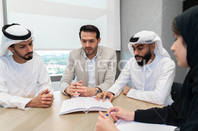 طلاب  عرب إماراتين  خليجيين في الجامعه, استاذ جامعة يناقش الطلاب المواد الدراسية , مشاركة المعلومات الدراسيه, مشروع جماعي, بحث علمي, مدربين جامعيين, اجتماع فريق عمل داخل الفصل , تحديد استراتيجيات وأهداف العمل, وحدة العمل الجماعي