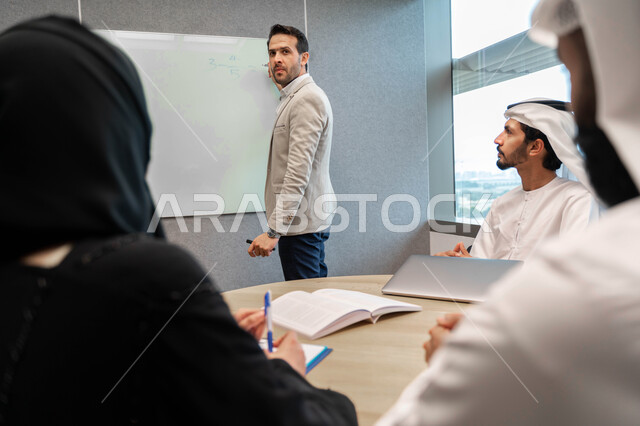 مدرب  يشرح لطلاب وطالبات عرب خليجيين و إماراتين  المحاضره, مدرب جامعي, يدون الملاحظات على السبوره, التعليم الجامعي في الإمارات العربية المتحدة , فريق عمل عربي إماراتي  خليجي