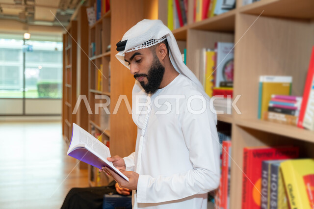 Arab Gulf Emirati student in the university library, reading a book inside the library, taking notes, borrowing a suitable book, studying in the university library, enriching university education, scientific research, the concept of science and learning