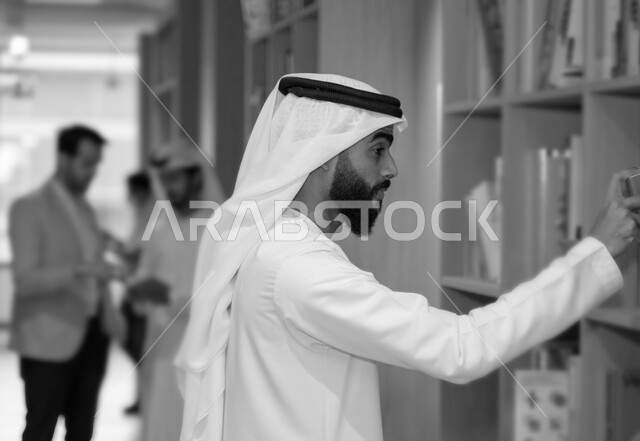 A black and white picture of Emirati Gulf Arab students in the university library, reading a book inside the library, taking notes, borrowing a suitable book, studying in the university library, enriching university education, scientific research, the con