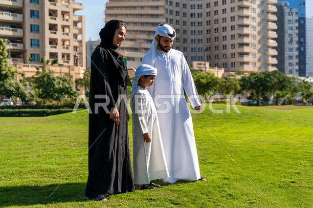 عائله عربيه إماراتية خليجيه مكونه من ثلاث أفراد, قضاء وقت ممتع في الحديقه, رحله عائليه, مفهوم الأسره السعيده, إجازه صيفيه, الاستمتاع باللعب الجماعي في المنتزه, تسليه وترفيه