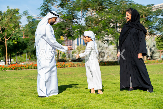 عائله عربيه إماراتية خليجيه مكونه من ثلاث أفراد, قضاء وقت ممتع في الحديقه, رحله عائليه, مفهوم الأسره السعيده, إجازه صيفيه, الاستمتاع باللعب الجماعي في المنتزه, تسليه وترفيه