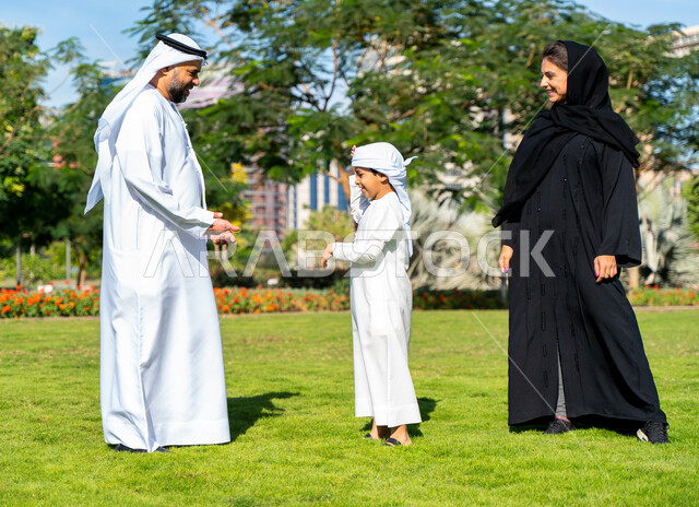 عائله عربيه إماراتية خليجيه مكونه من ثلاث أفراد, قضاء وقت ممتع في الحديقه, رحله عائليه, مفهوم الأسره السعيده, إجازه صيفيه, الاستمتاع باللعب الجماعي في المنتزه, تسليه وترفيه