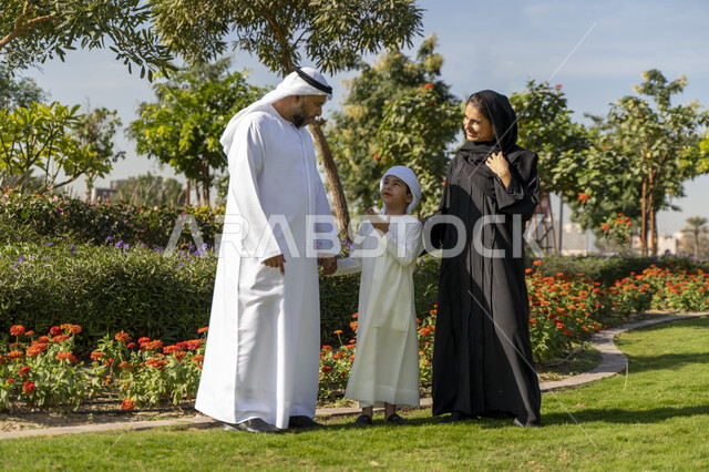 عائله عربيه إماراتية خليجيه مكونه من ثلاث أفراد, قضاء وقت ممتع في الحديقه, رحله عائليه, مفهوم الأسره السعيده, إجازه صيفيه, الاستمتاع باللعب الجماعي في المنتزه, تسليه وترفيه