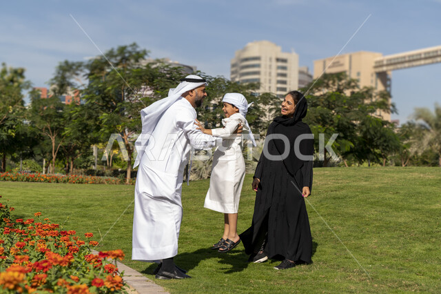 عائله عربيه إماراتية خليجيه مكونه من ثلاث أفراد, أب إماراتي يلعب مع ولده ويرفع به عاليا , قضاء وقت ممتع في الحديقه, رحله عائليه, مفهوم الأسره السعيده, إجازه صيفيه, الاستمتاع باللعب الجماعي في المنتزه, تسليه وترفيه