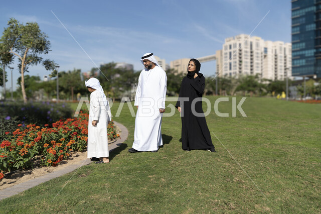 عائله عربيه إماراتية خليجيه مكونه من ثلاث أفراد, قضاء وقت ممتع في الحديقه, رحله عائليه, مفهوم الأسره السعيده, إجازه صيفيه, الاستمتاع باللعب الجماعي في المنتزه, تسليه وترفيه
