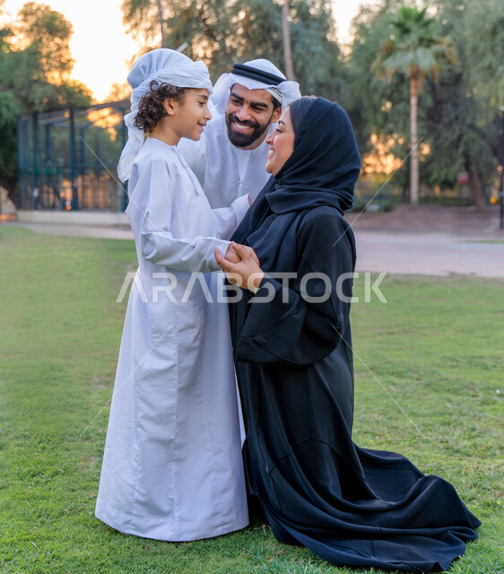عائله عربيه إماراتيه  خليجيه مكونه من ثلاث أفراد, قضاء وقت ممتع في الحديقه, رحله عائليه عند غروب الشمس , مفهوم الأسره السعيده, إجازه صيفيه, الاستمتاع باللعب الجماعي في المنتزه, تسليه وترفيه, عطلة نهاية الاسبوع