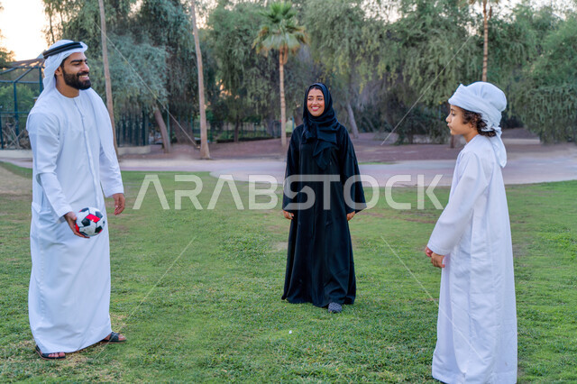عائله عربيه إماراتيه  خليجيه مكونه من ثلاث أفراد, قضاء وقت ممتع في الحديقه عند غروب الشمس , اللعب الجماعي بالكره في المنتزه, تسليه وترفيه, عطلة نهاية الاسبوع