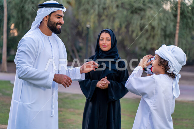 عائله عربيه إماراتيه  خليجيه مكونه من ثلاث أفراد, قضاء وقت ممتع في الحديقه عند غروب الشمس , اللعب الجماعي بالكره في المنتزه, تسليه وترفيه, عطلة نهاية الاسبوع