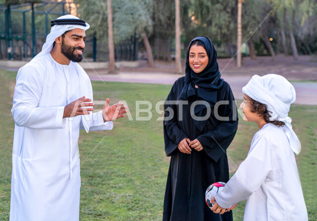 عائله عربيه إماراتيه  خليجيه مكونه من ثلاث أفراد, قضاء وقت ممتع في الحديقه عند غروب الشمس , اللعب الجماعي بالكره في المنتزه, تسليه وترفيه, عطلة نهاية الاسبوع