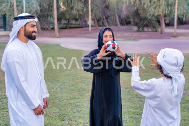 عائله عربيه إماراتيه  خليجيه مكونه من ثلاث أفراد, قضاء وقت ممتع في الحديقه عند غروب الشمس , اللعب الجماعي بالكره في المنتزه, تسليه وترفيه, عطلة نهاية الاسبوع