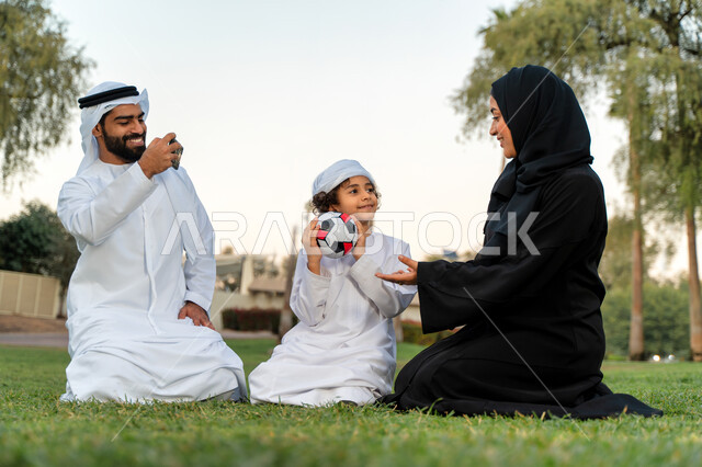 عائله عربيه إماراتيه  خليجيه مكونه من ثلاث أفراد, قضاء وقت ممتع في الحديقه عند غروب الشمس , اللعب الجماعي بالكره في المنتزه, تسليه وترفيه, عطلة نهاية الاسبوع