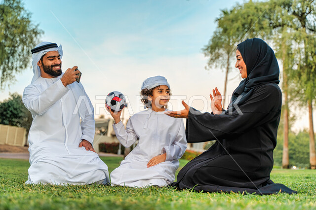 عائله عربيه إماراتيه  خليجيه مكونه من ثلاث أفراد, قضاء وقت ممتع في الحديقه عند غروب الشمس , اللعب الجماعي بالكره في المنتزه, تسليه وترفيه, عطلة نهاية الاسبوع