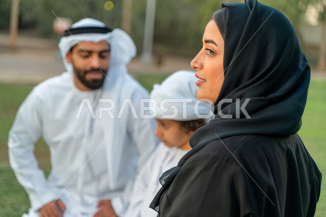عائله عربيه إماراتيه  خليجيه مكونه من ثلاث أفراد, قضاء وقت ممتع في الحديقه, الإشارة الى شيء ما, رحله عائليه في يوم مشمس, مفهوم الأسره السعيده, إجازه صيفيه, الاستمتاع باللعب الجماعي في المنتزه, تسليه وترفيه, عطلة نهاية الاسبوع