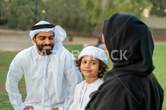 عائله عربيه إماراتيه  خليجيه مكونه من ثلاث أفراد, قضاء وقت ممتع في الحديقه, ايماءات وجه تدل على السعادة , النظر الى بعضهم البعض بكل حب ,  رحله عائليه في يوم مشمس, مفهوم الأسره السعيده, إجازه صيفيه, الاستمتاع باللعب الجماعي في المنتزه, تسليه وترفيه, عطلة ن