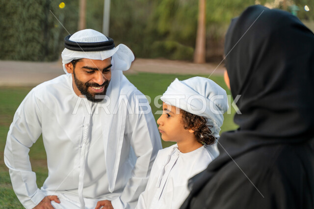 عائله عربيه إماراتيه  خليجيه مكونه من ثلاث أفراد, قضاء وقت ممتع في الحديقه, ايماءات وجه تدل على السعادة , النظر الى بعضهم البعض بكل حب ,  رحله عائليه في يوم مشمس, مفهوم الأسره السعيده, إجازه صيفيه, الاستمتاع باللعب الجماعي في المنتزه, تسليه وترفيه, عطلة ن