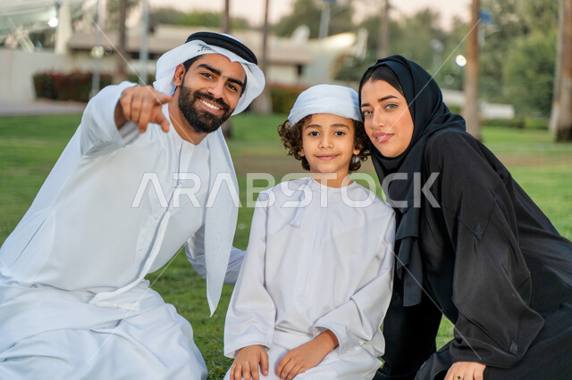 عائله عربيه إماراتيه  خليجيه مكونه من ثلاث أفراد, قضاء وقت ممتع في الحديقه, الإشارة الى شيء ما, رحله عائليه في يوم مشمس, مفهوم الأسره السعيده, إجازه صيفيه, الاستمتاع باللعب الجماعي في المنتزه, تسليه وترفيه, عطلة نهاية الاسبوع